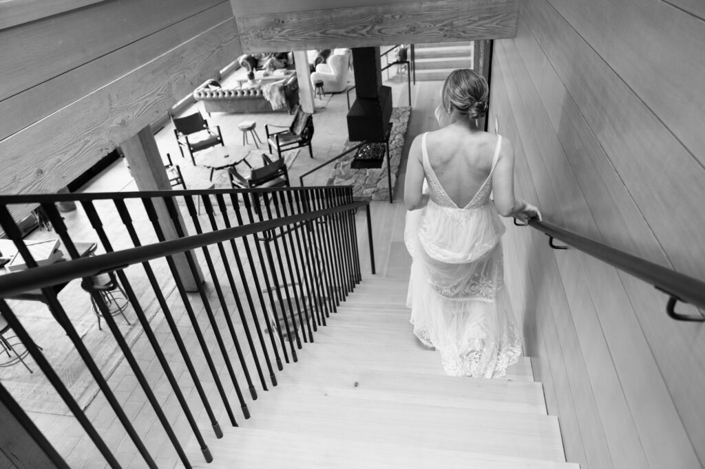 A bride walks down a set of stairs towards her first look at the Black Walnut Inn
