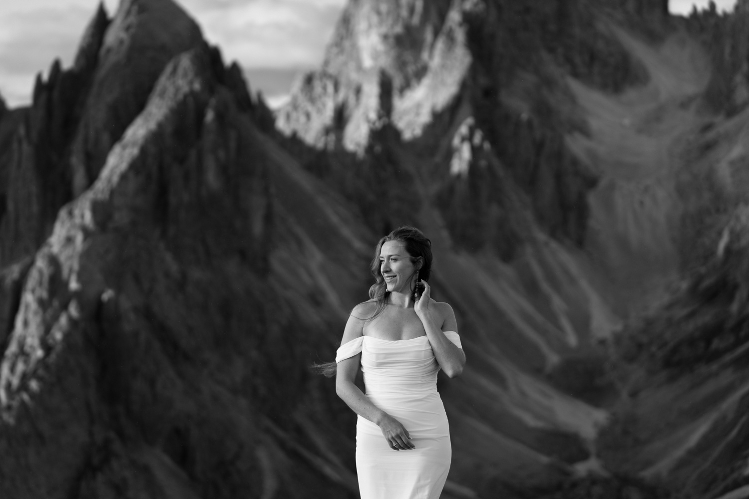 A black and white photo of a bride standing in front of Cadini di Misurina mountains during her Italian Dolomites elopement.