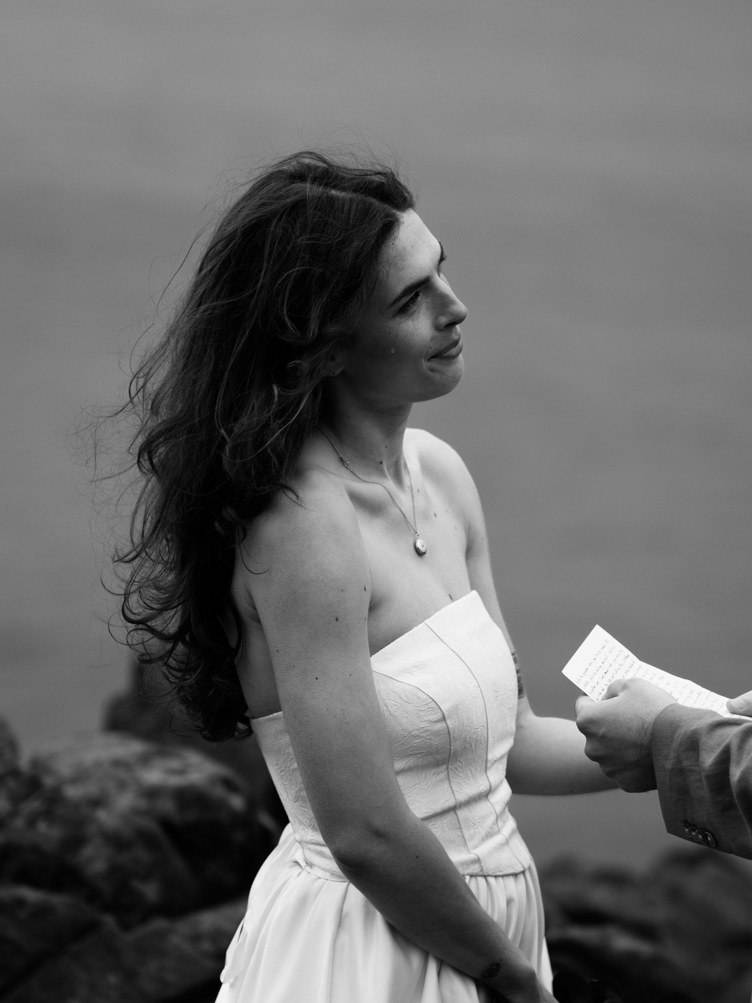 Black and white side profile portrait of a person with windswept hair, eyes closed, on the Oregon Coast