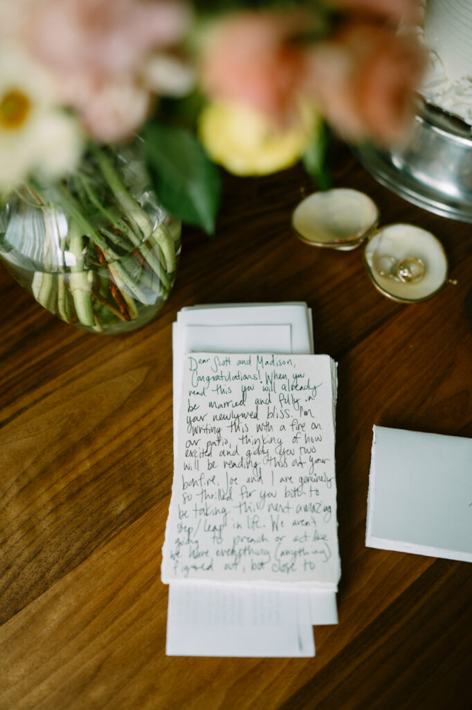 Close-up of a handwritten letter from family and friends, held over a wooden table, warm golden inn light