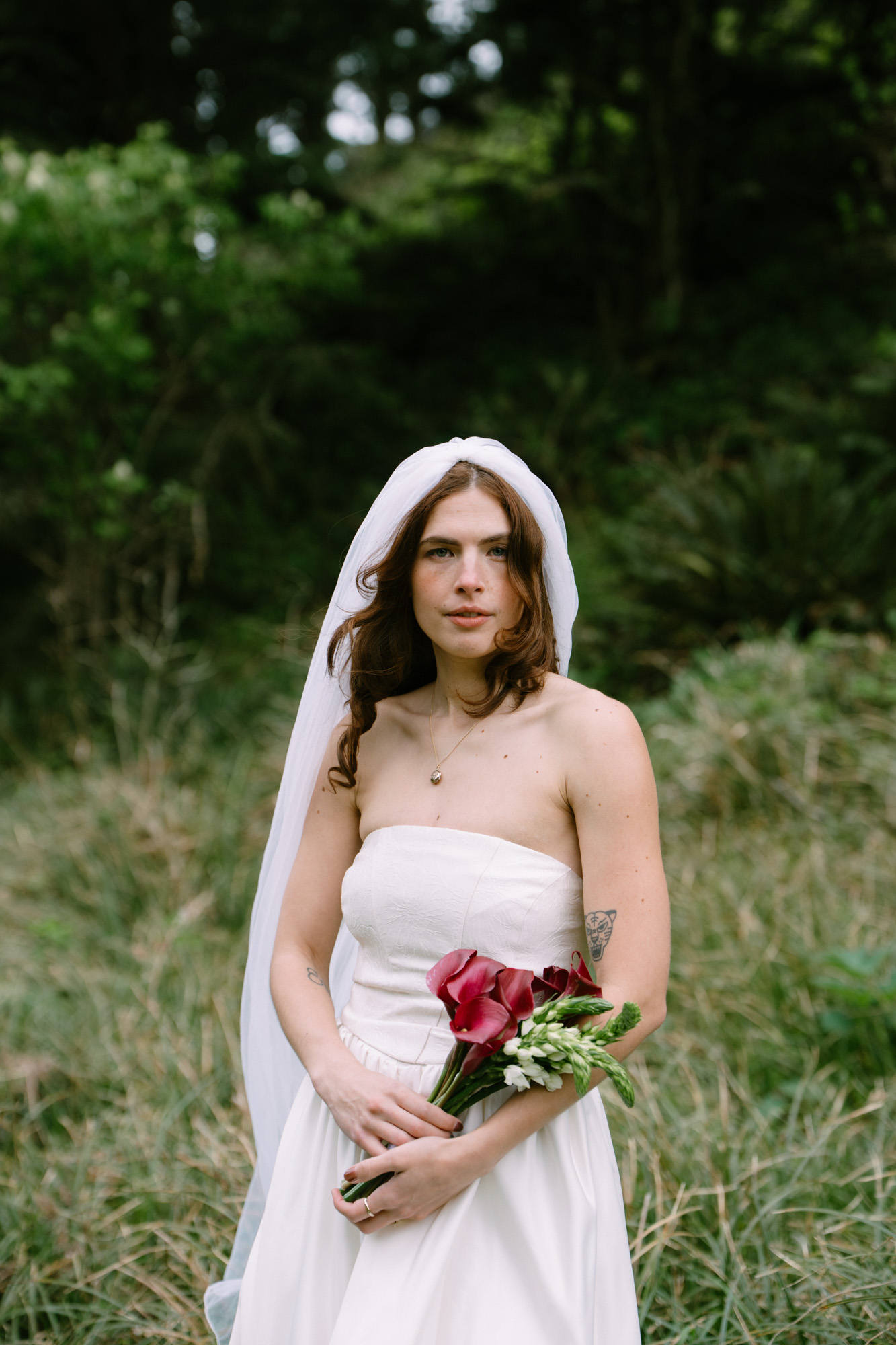 Portrait of a person in a strapless white wedding dress standing among towering evergreen trees at Elk Flats