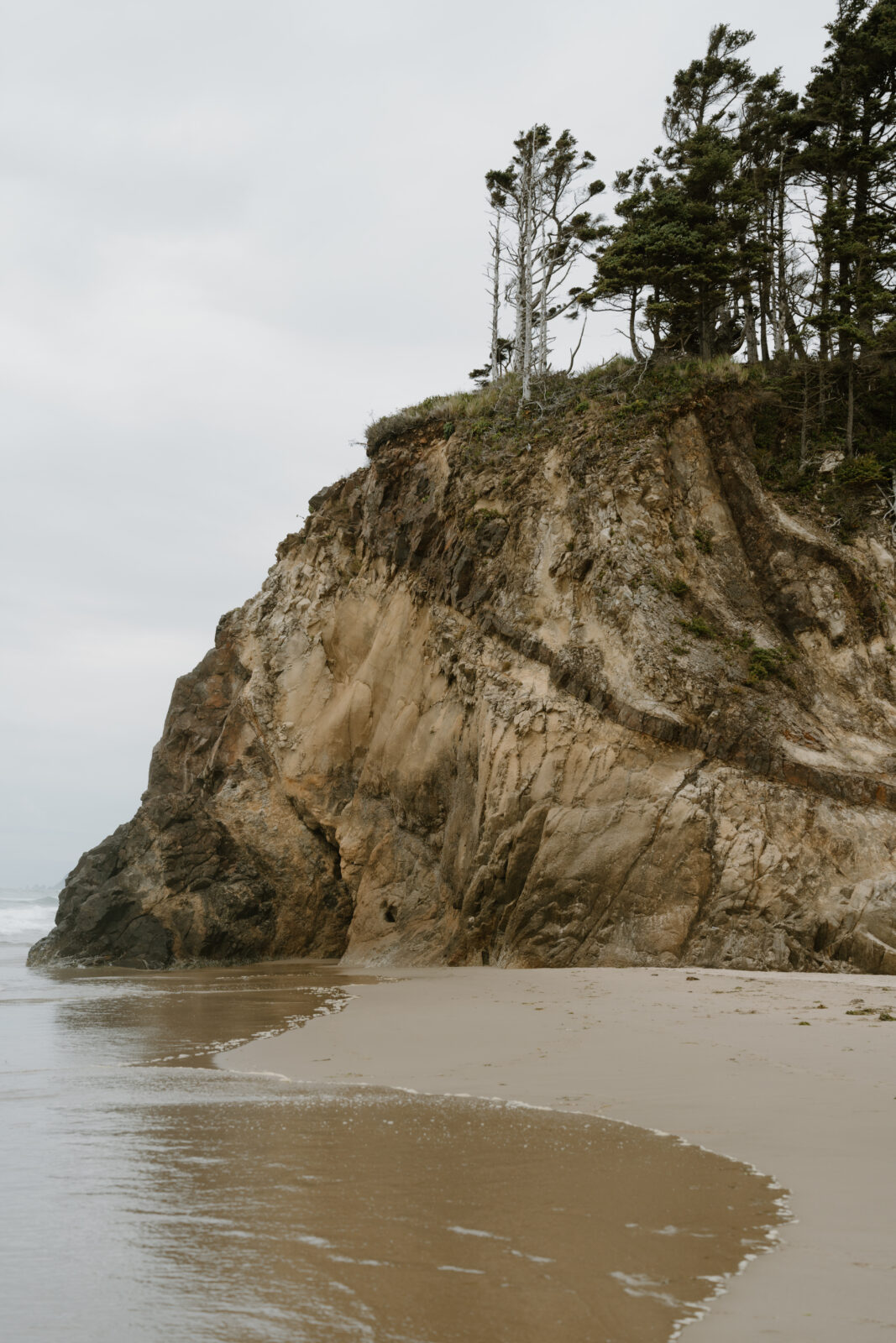 Micro-wedding photos at Hug Point on the Oregon Coast. Featuring sandy beaches and tall, imposing rock formations