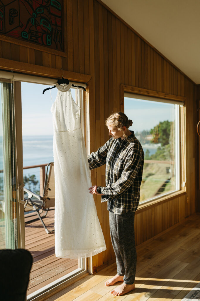 A wedding dress hangs in a rental before an Oregon Coast elopement. 