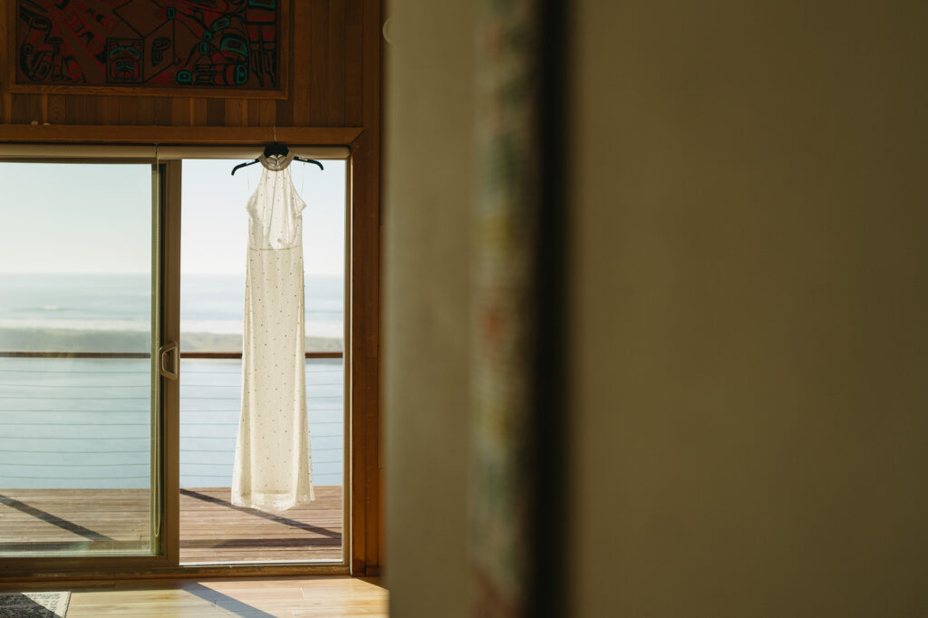 A wedding dress hangs in a rental before an Oregon Coast elopement. 