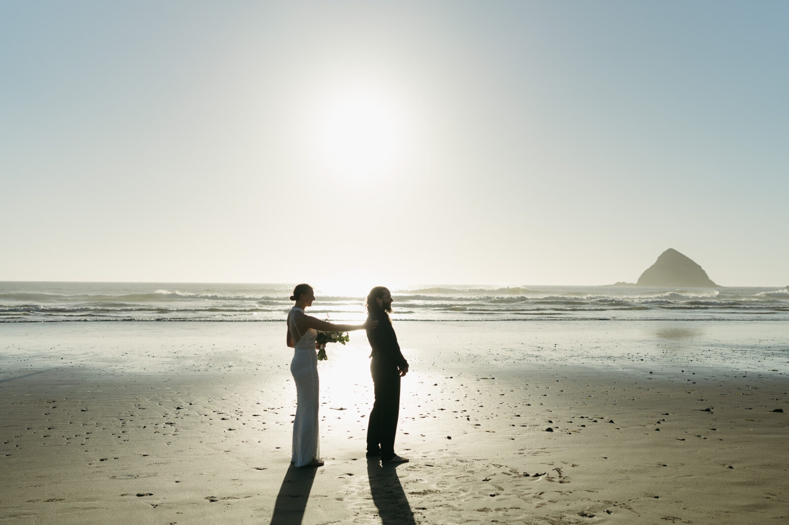 A couple elopes on the rugged Oregon Coast a sunset. 