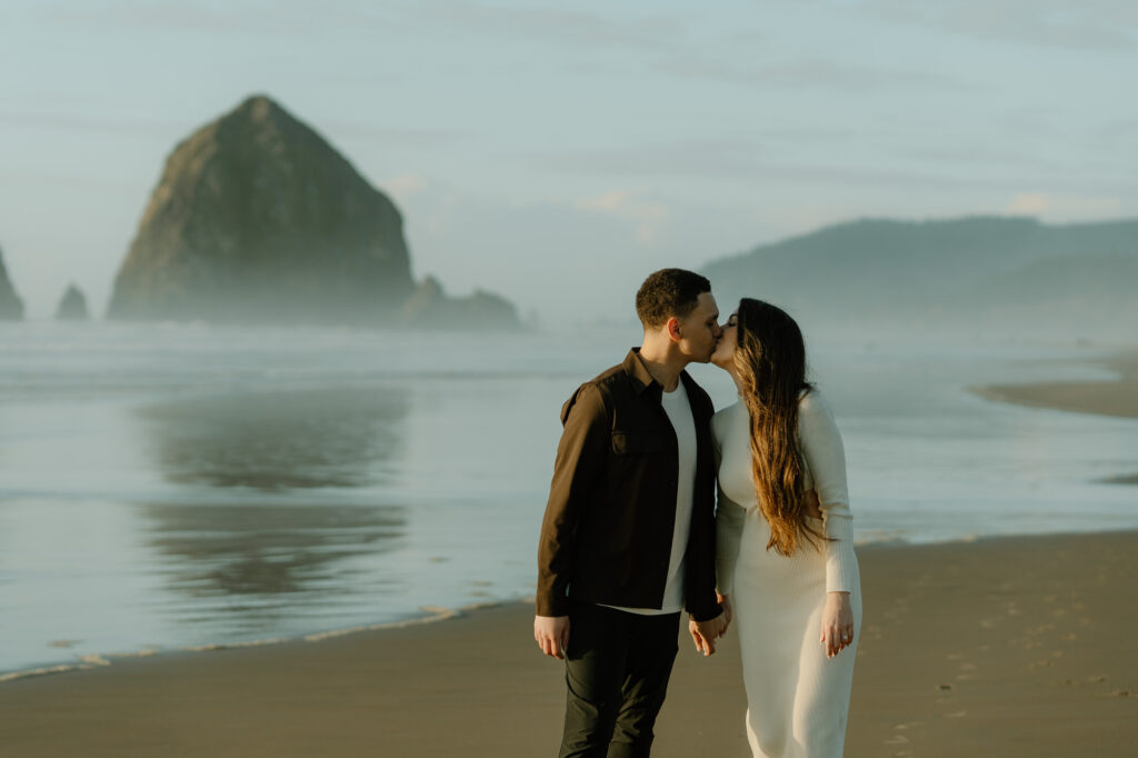 A couple kisses on Cannon Beach during their engagement photo shoot. 