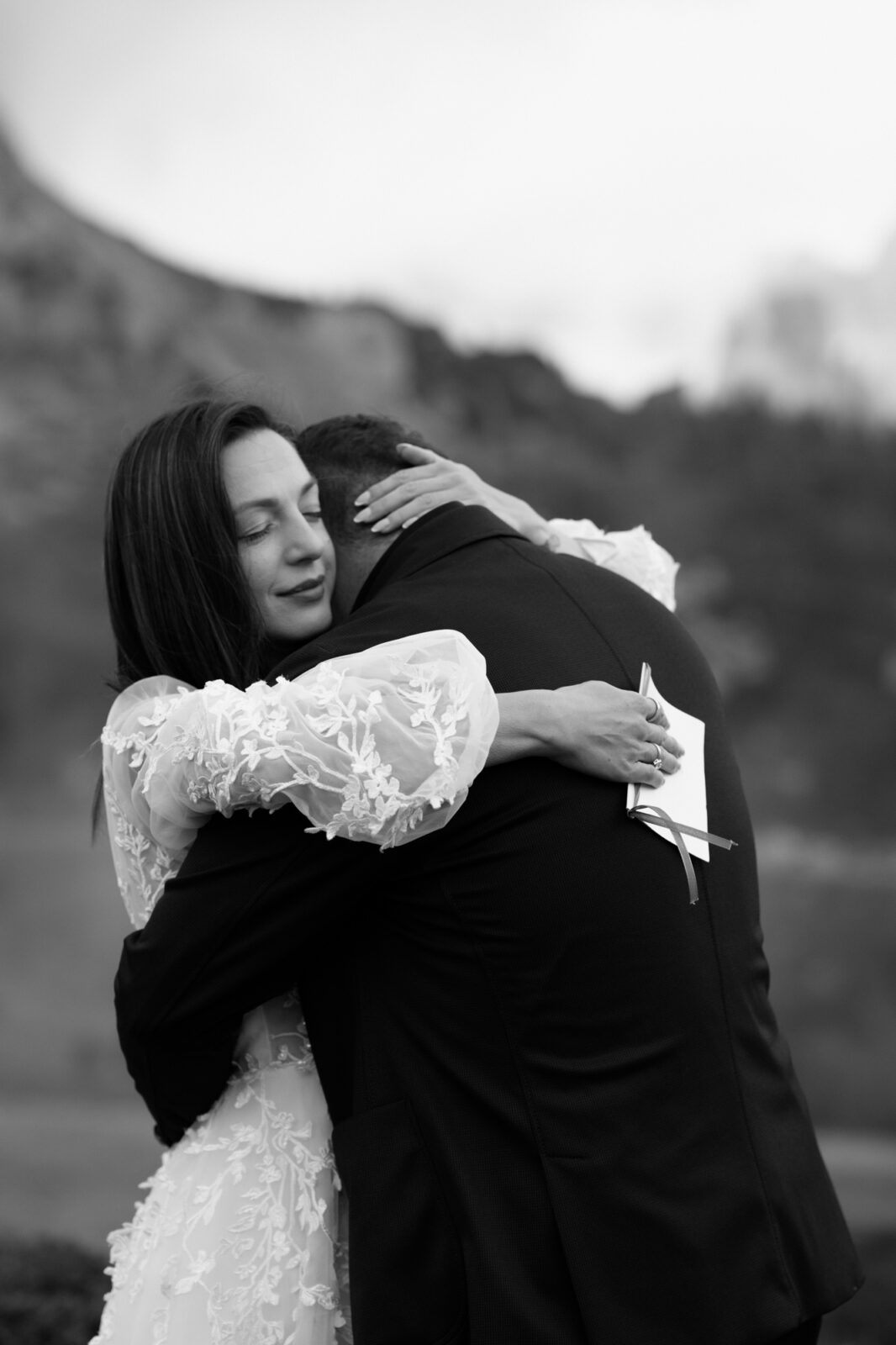 A black and white photo of an emotional couple exchanging wedding vows in front of the mountains during their Lago di Braies elopement. 