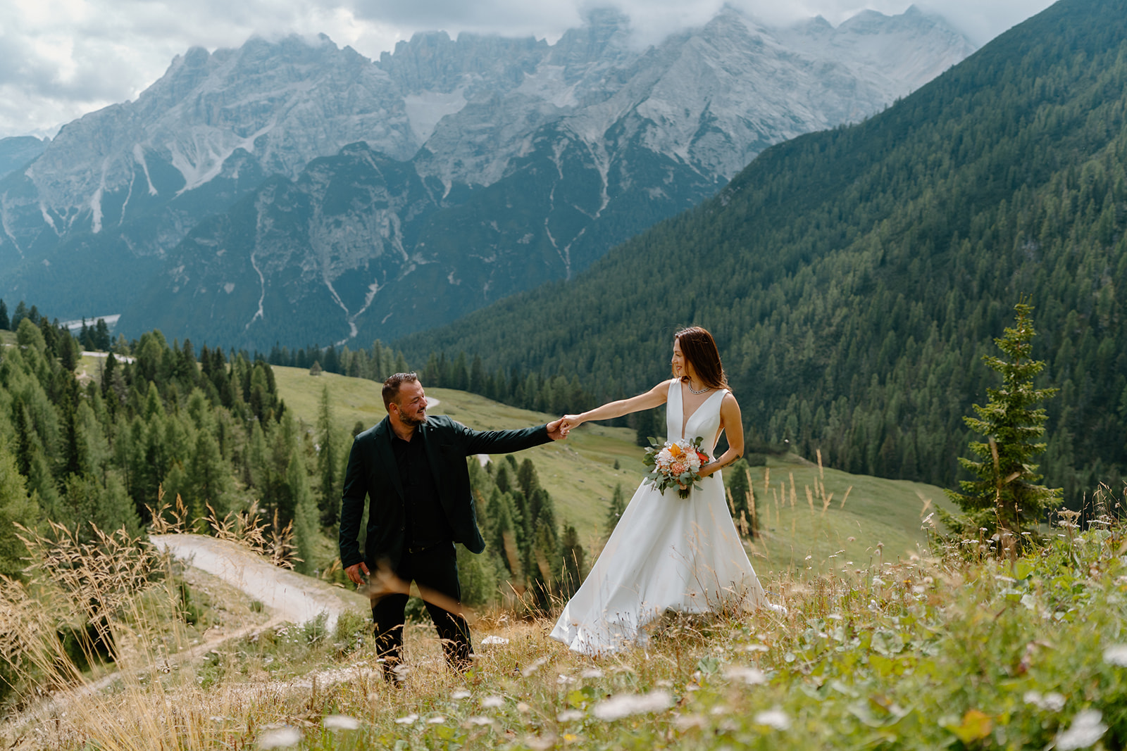 A couple poses in an alpine meadow for their Dolomites elopement photos.