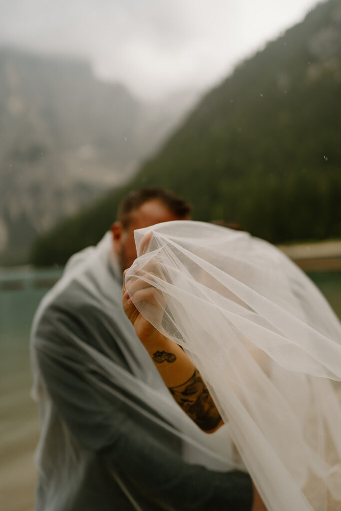 A couple poses for photos during their elopement at Lago di Braies in the Italian Dolomites.