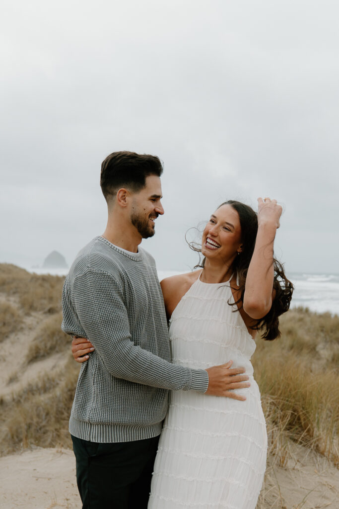 A couple laughs together for their Oregon Coast engagement photos.