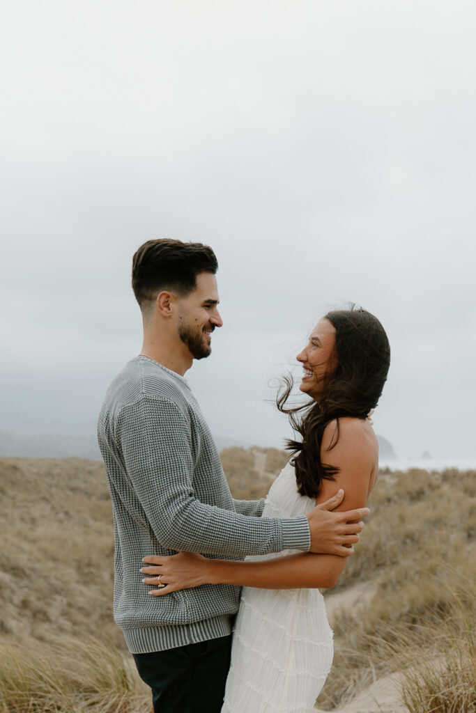 A couple laughs together for their Oregon Coast engagement photos.