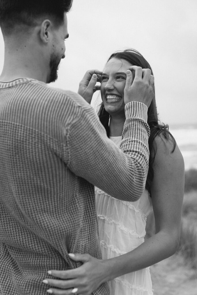 A couple laughs together for their Oregon Coast engagement photos.