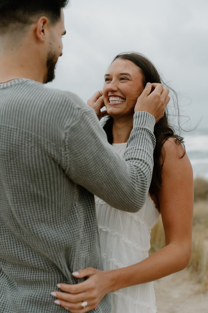 A couple laughs together for their Oregon Coast engagement photos.