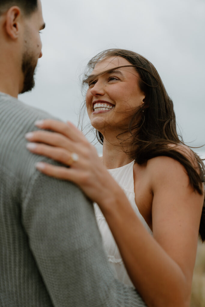 A couple laughs together for their Oregon Coast engagement photos.