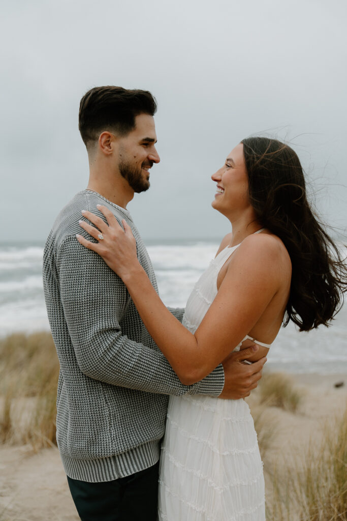 A couple laughs together for their Oregon Coast engagement photos.