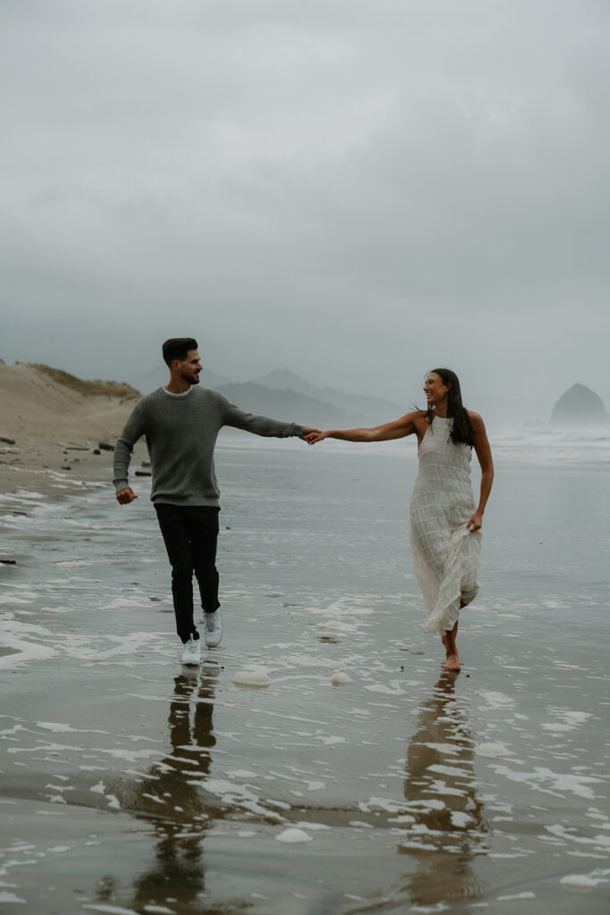 A couple plays on the beach for their Oregon Coast engagement photos.