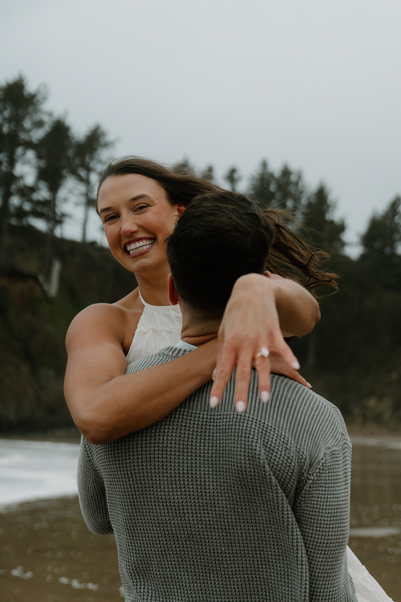 A couple plays on the beach for their Oregon Coast engagement photos.
