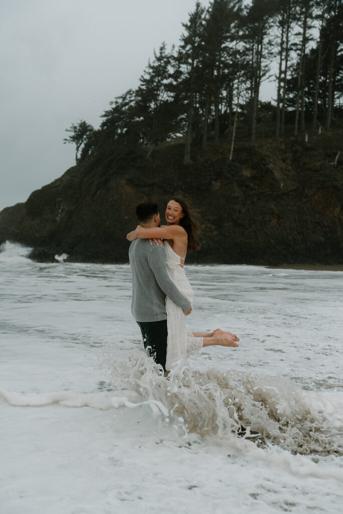 A couple plays on the beach for their Oregon Coast engagement photos.