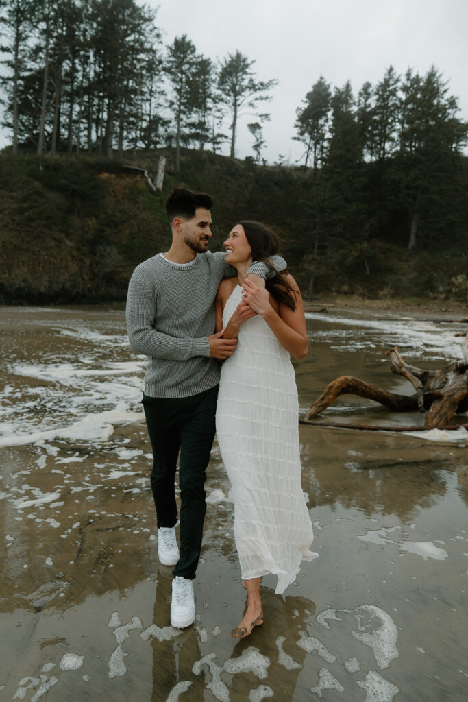 A couple plays on the beach for their Oregon Coast engagement photos.