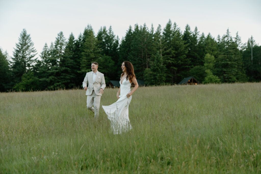 A couple laughs in a field together during their Wind Mountain Ranch wedding. 