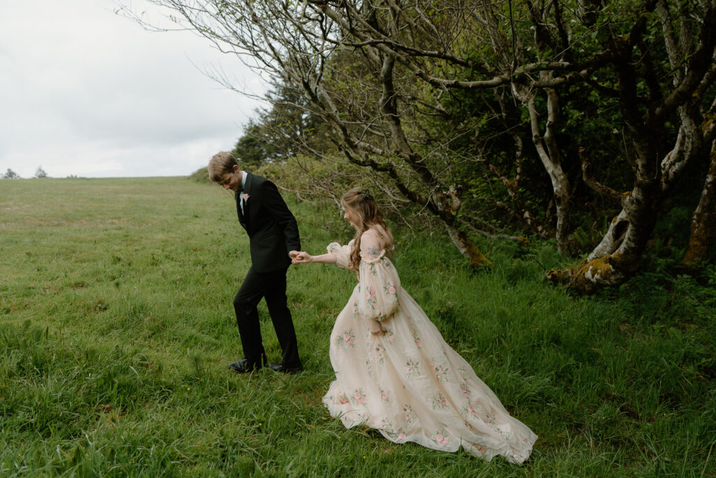 A couple walks out of the trees onto a fiend during their cannon beach elopement.