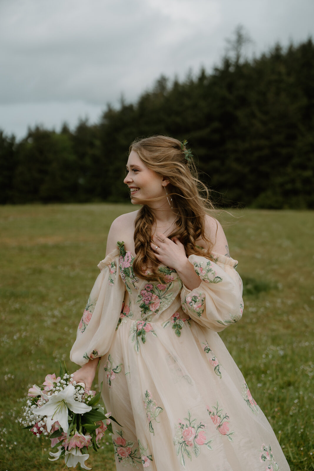 A bride poses in a field during her cannon beach elopement