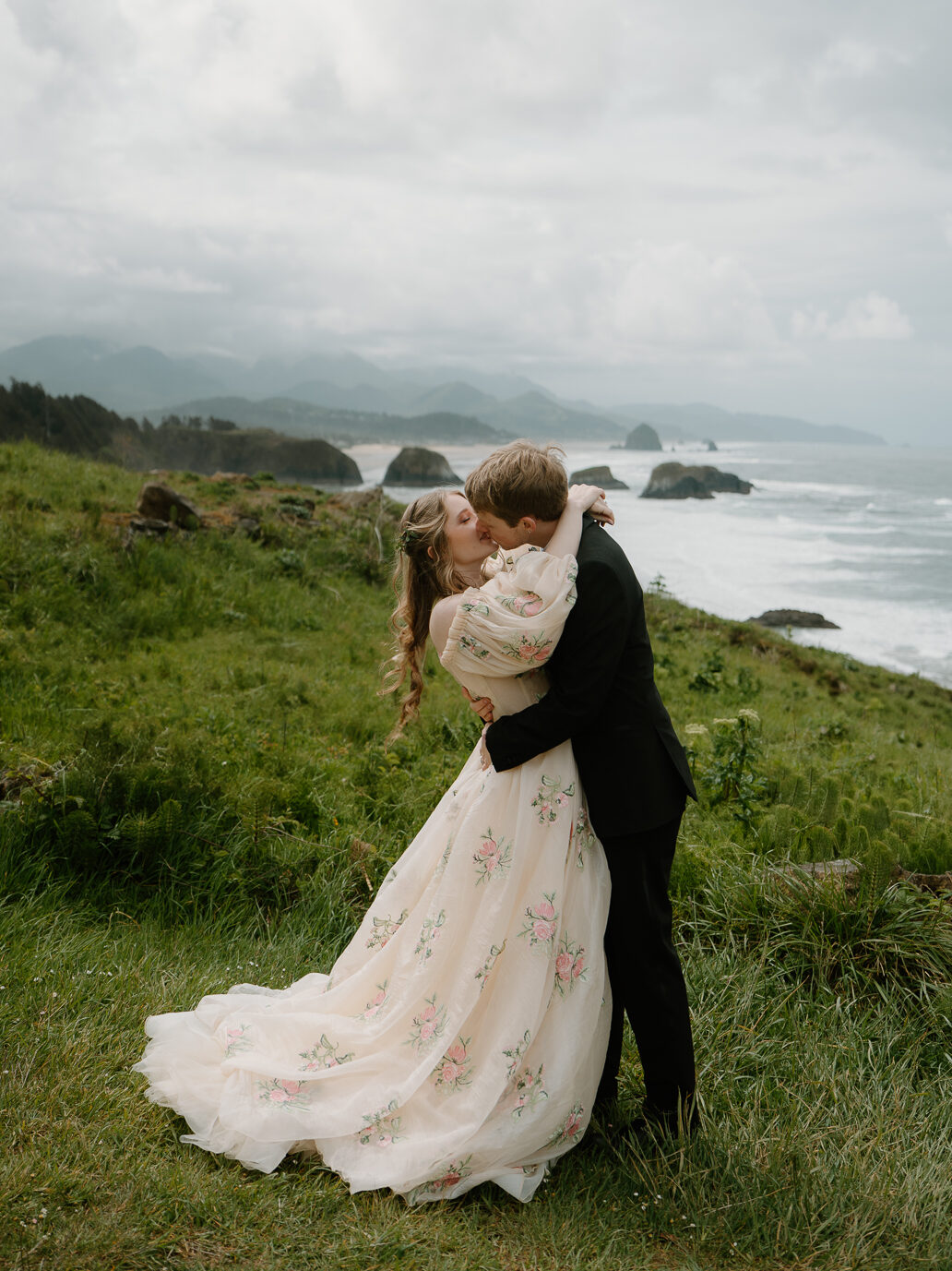 A couple kisses dramatically on a cliffside during their Cannon Beach elopement