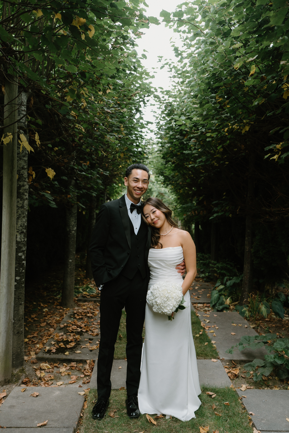 A couple in wedding attire snuggles together in a garden at their Briarwood Estate wedding.