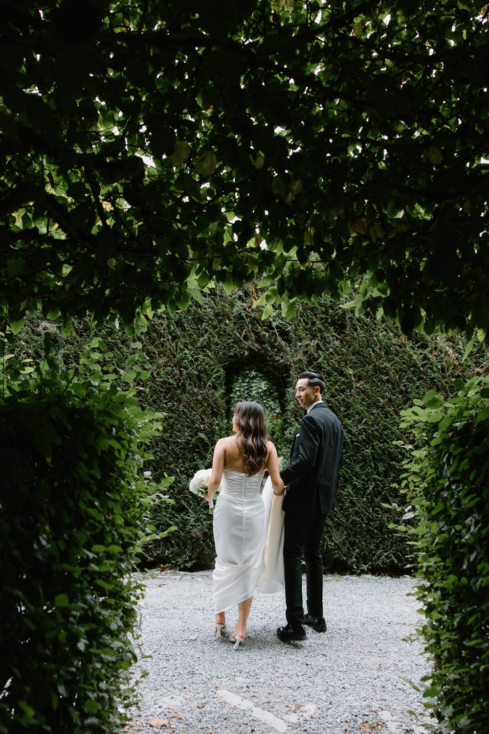 A couple in wedding attire snuggles together in a garden at their Briarwood Estate wedding.