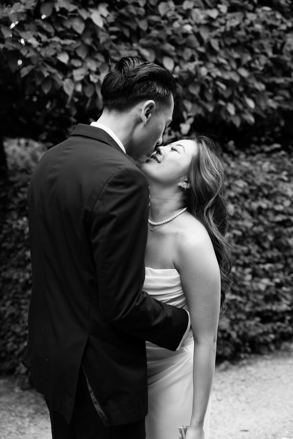 A couple in wedding attire snuggles together in a garden at their Briarwood Estate wedding.