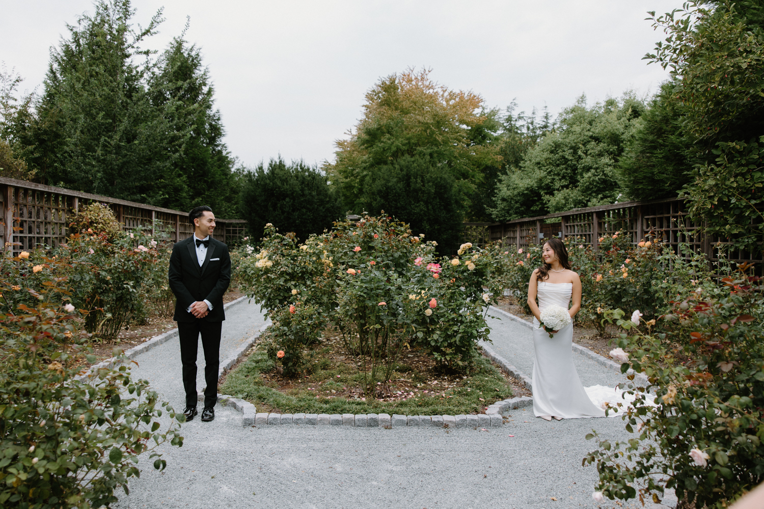 A couple in wedding attire snuggles together in a garden at their Briarwood Estate wedding.