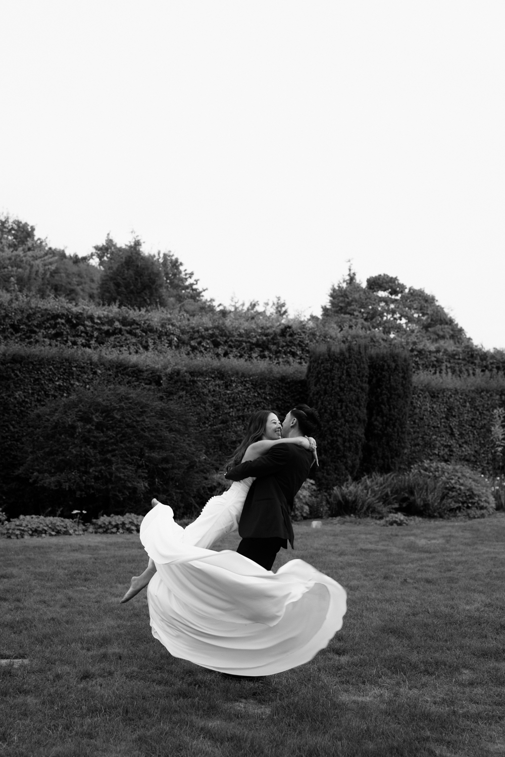 A couple in wedding attire runs through a field at sunset during their Briarwood Estate wedding.