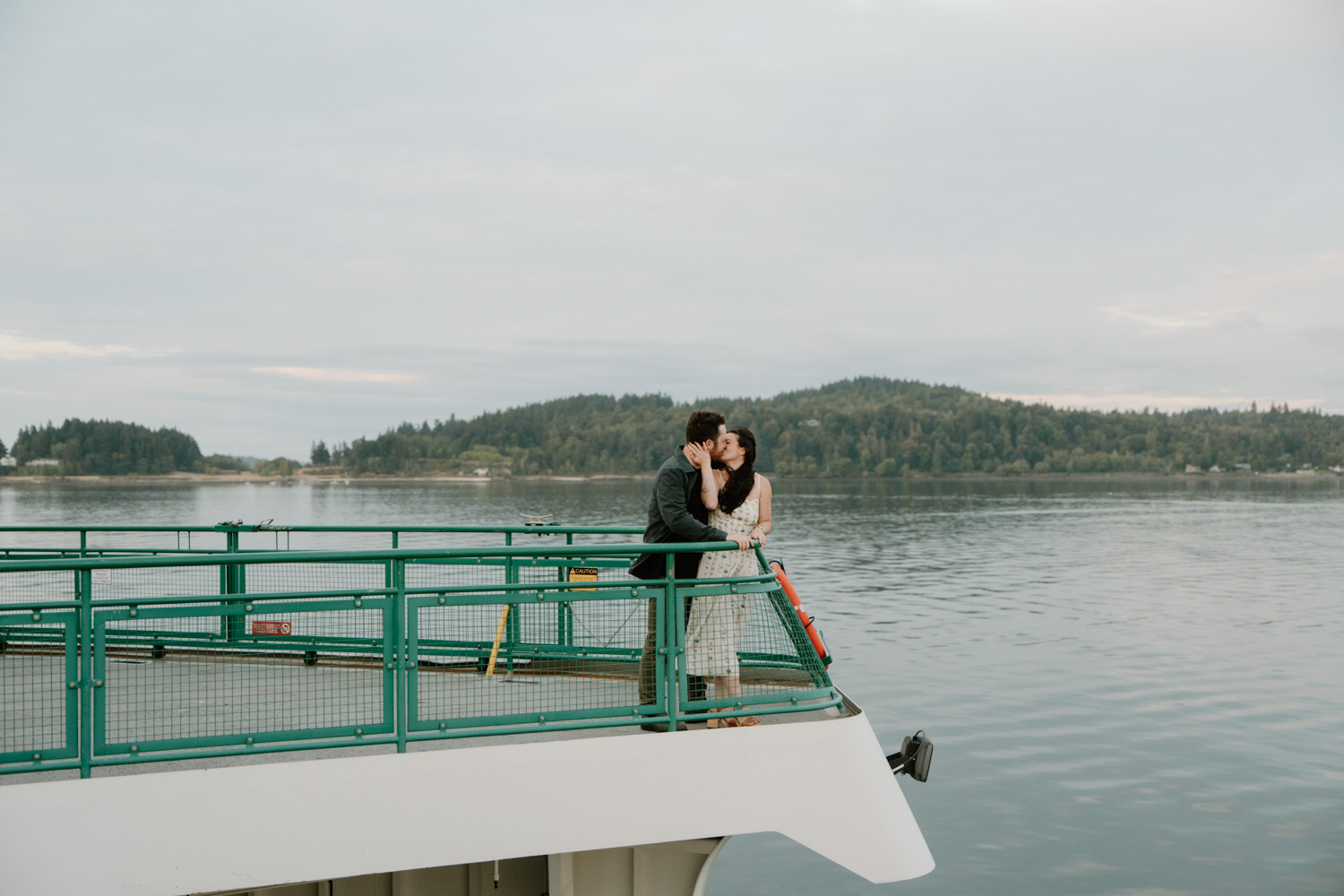 A couple kisses on a large ferry to Bainbridge Island for their Seattle engagement photos.