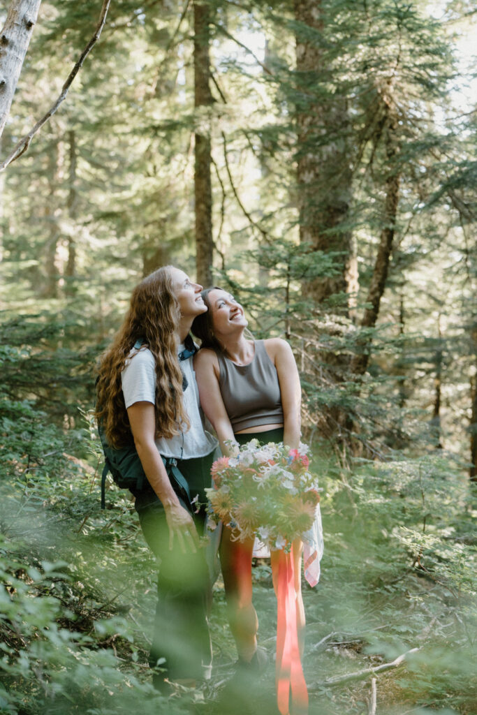 A couple hikes through the woods in hiking attire for their Mount Hood elopement