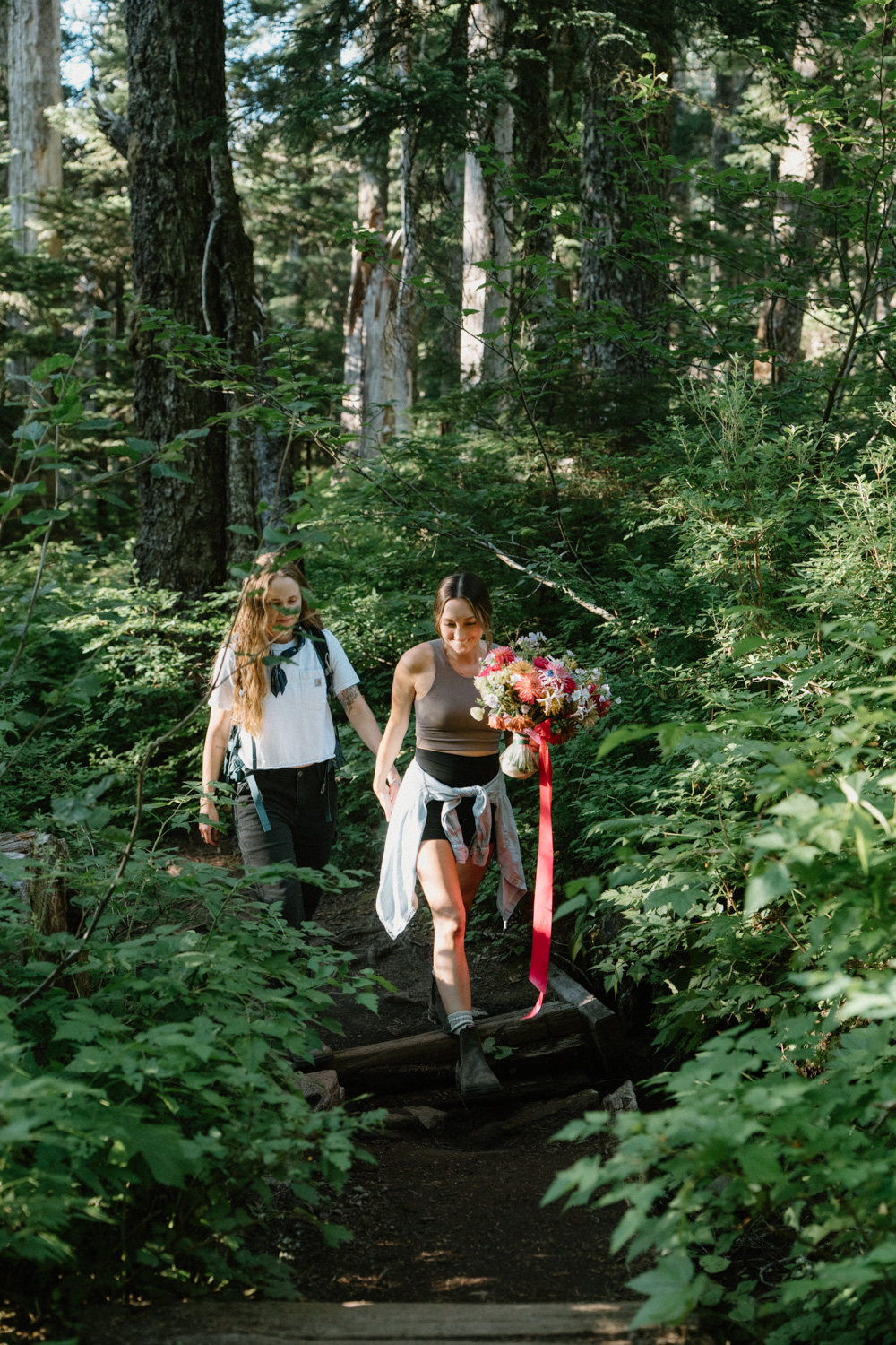A couple hikes through the woods in hiking attire for their Mount Hood elopement