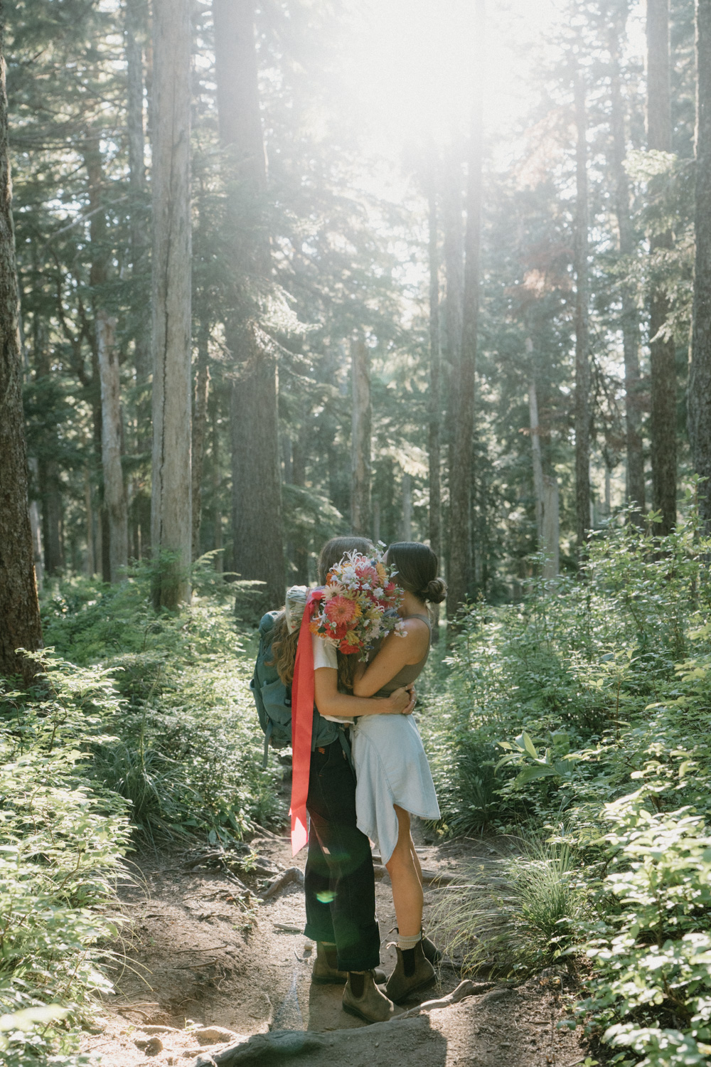A couple hikes through the woods in hiking attire for their Mount Hood elopement