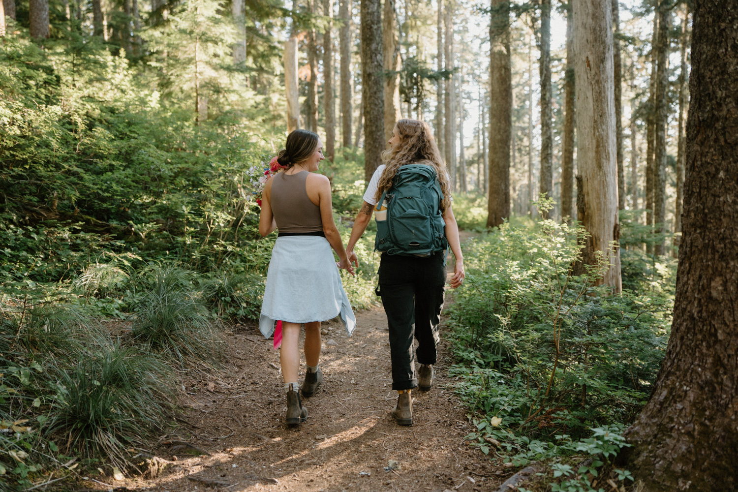 A couple hikes through the woods in hiking attire for their Mount Hood elopement