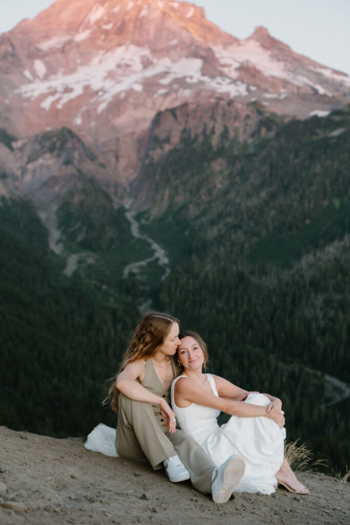 A couple snuggles in front of a pink mountain backdrop at sunset during their Mount Hood elopement
