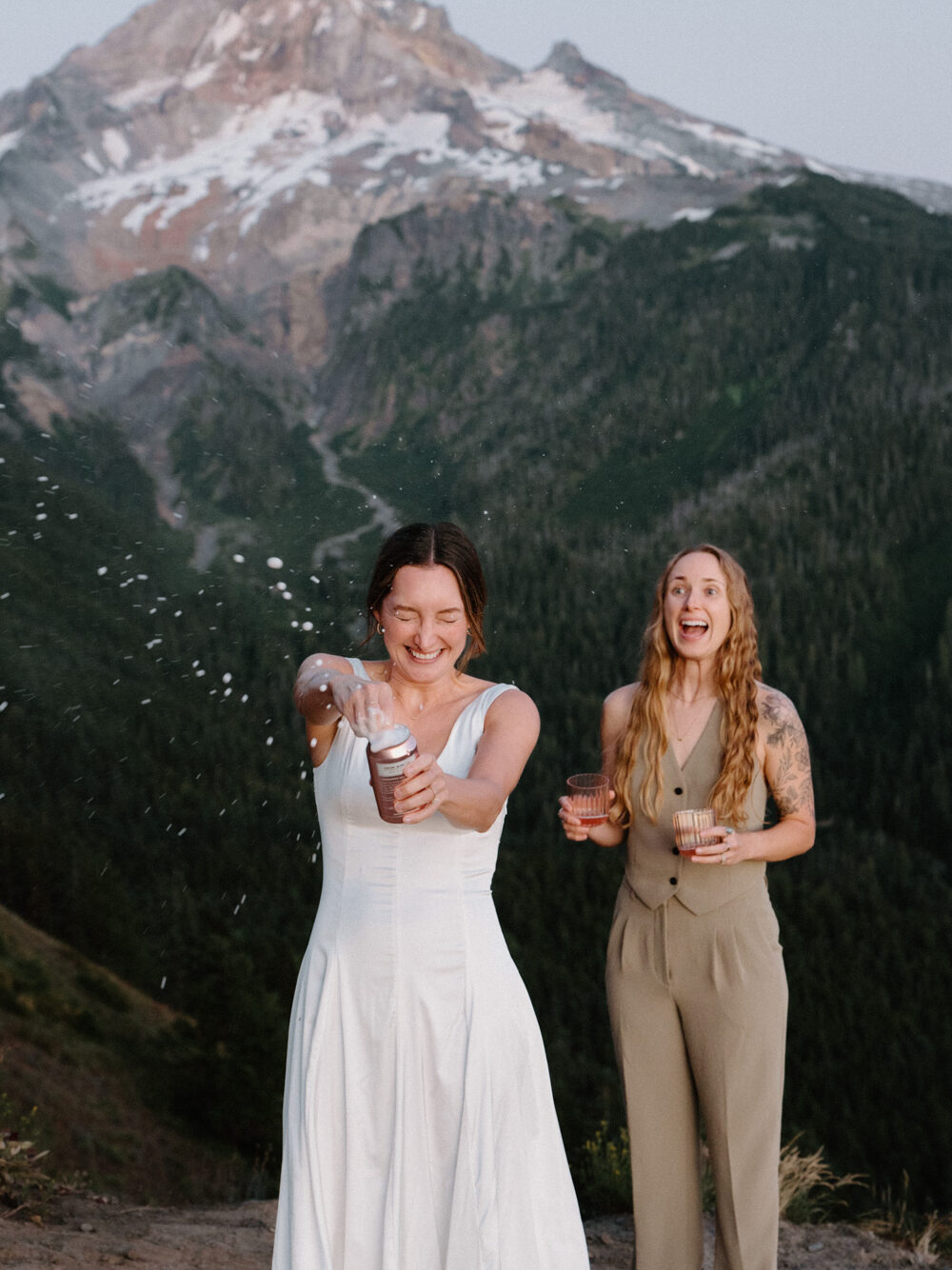 A couple opens wine in celebration of their Mount Hood elopement, with the mountain behind them.