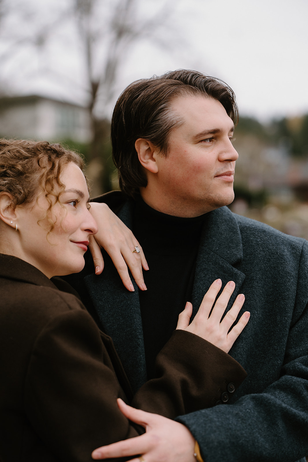 A couple snuggles on a shoreline in the winter Black and white photo of a couple walking in a park for their Seattle engagement photos