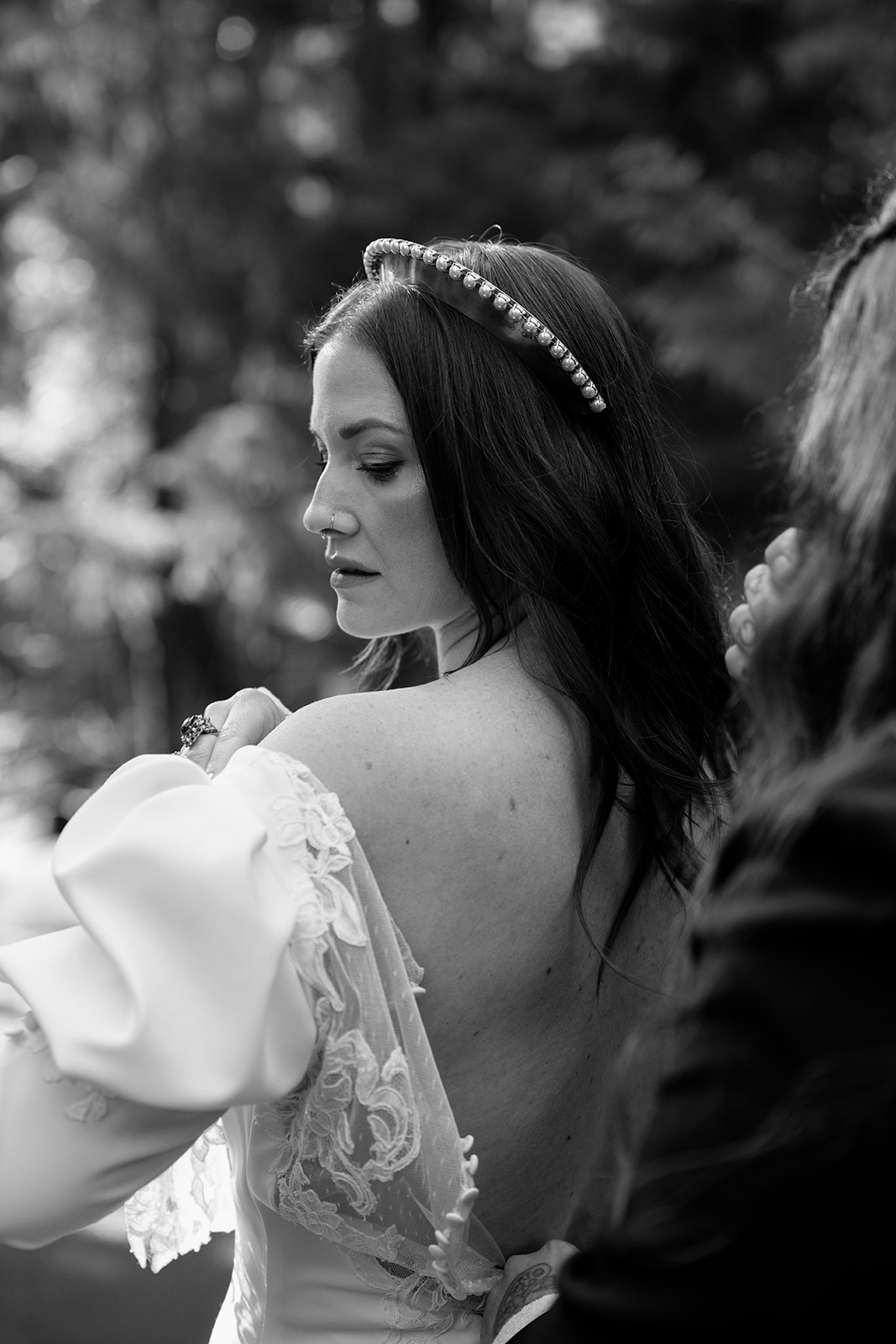 A black and white photo of a bride changing into her dress before her Sahalie Falls elopement. 