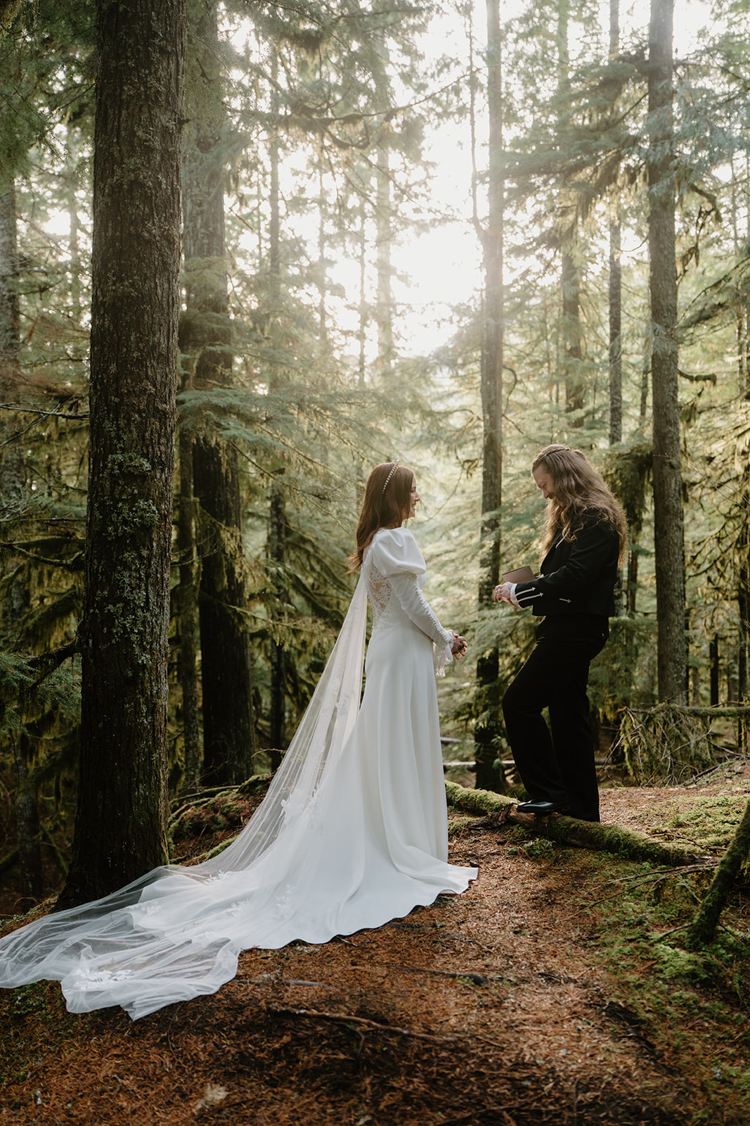 A couple in wedding attire privately exchange vows in the woods during their Sahalie Falls elopement. 