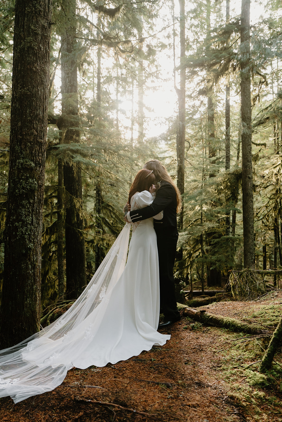 A couple in wedding attire privately exchange vows in the woods during their Sahalie Falls elopement. 