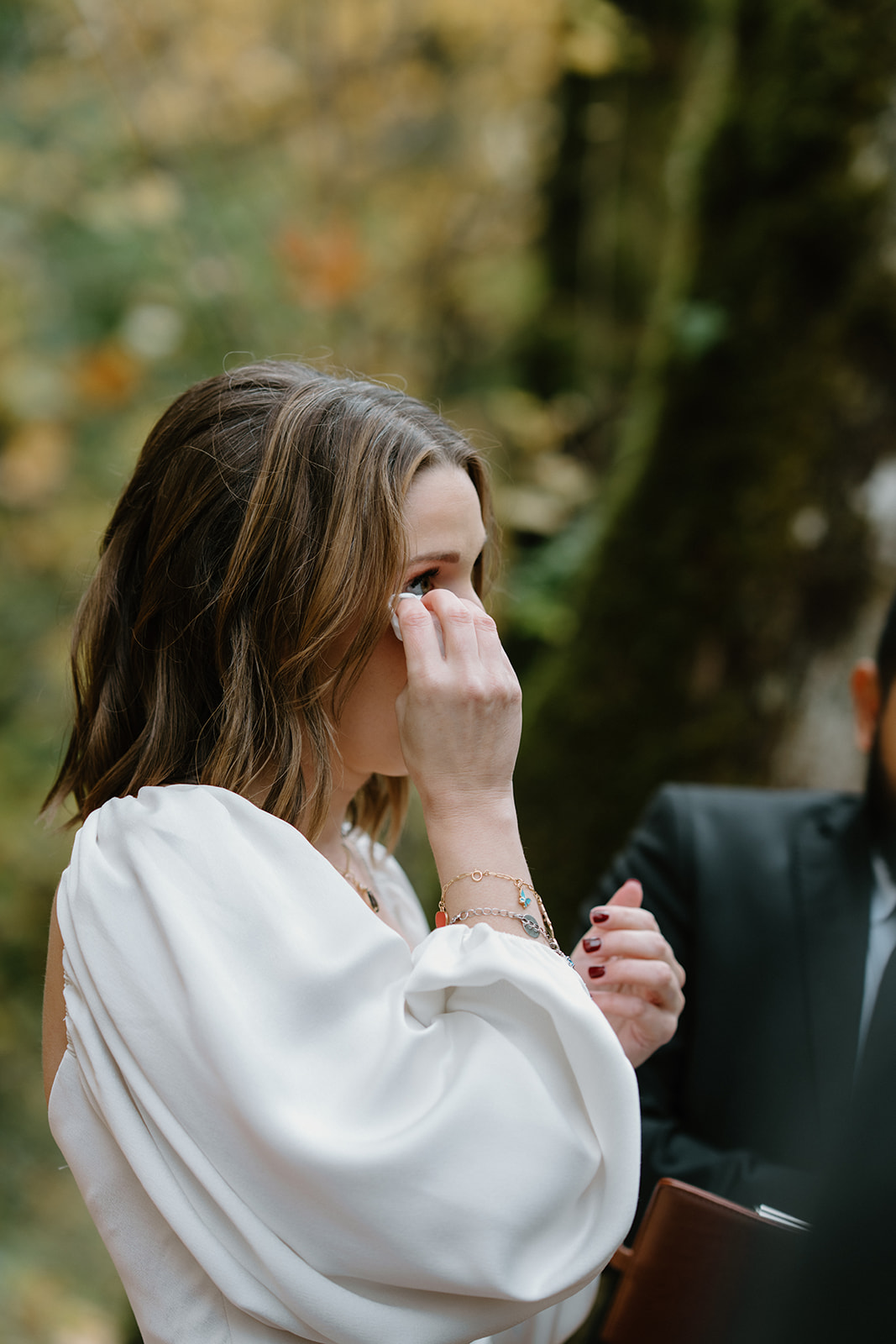 A bride wipes away tears as her husband reads his vows to her during their Latourell Falls elopement.