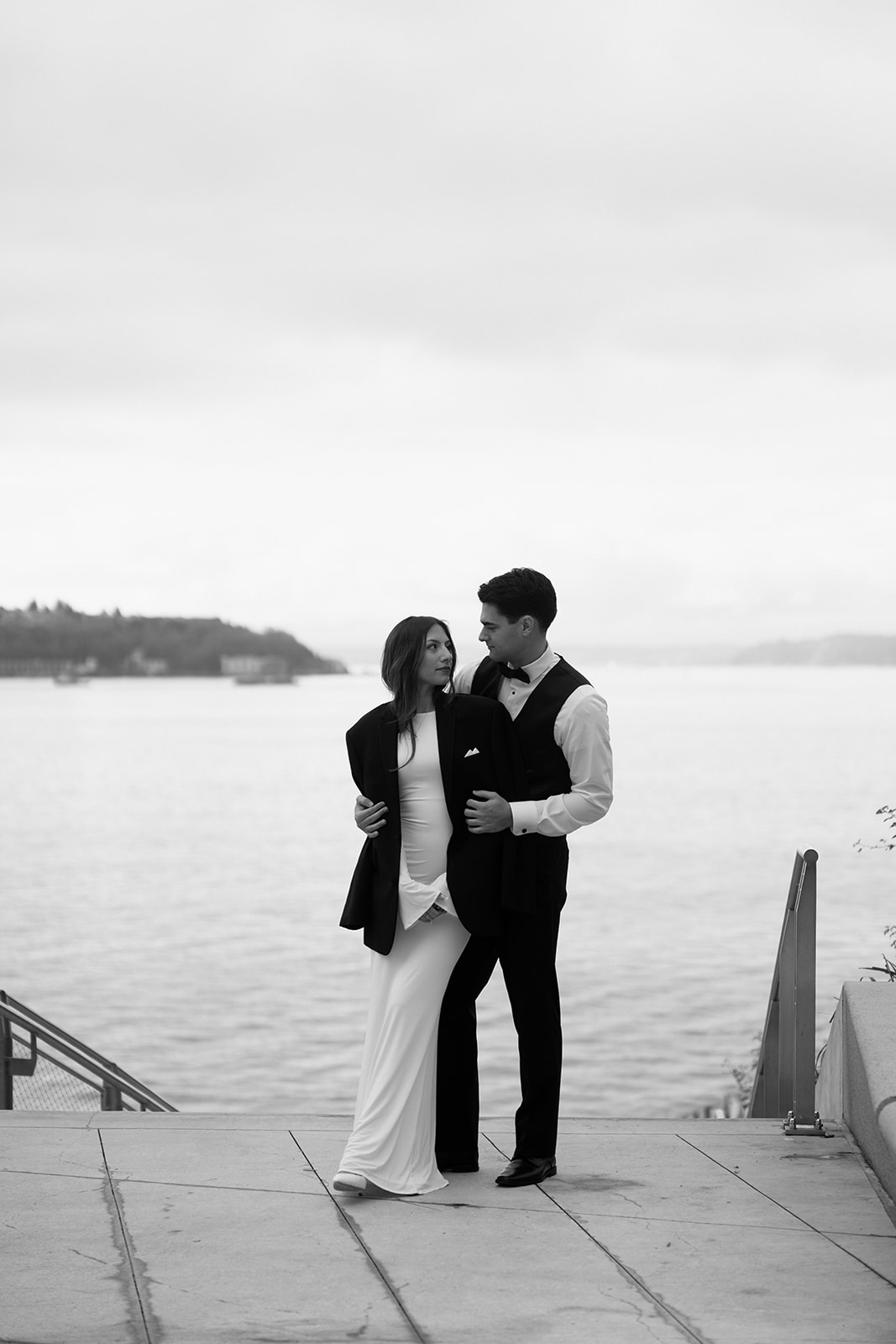 A black and white photo of a couple in wedding attire, facing the camera leaning into each other during a Pike Place elopement. 