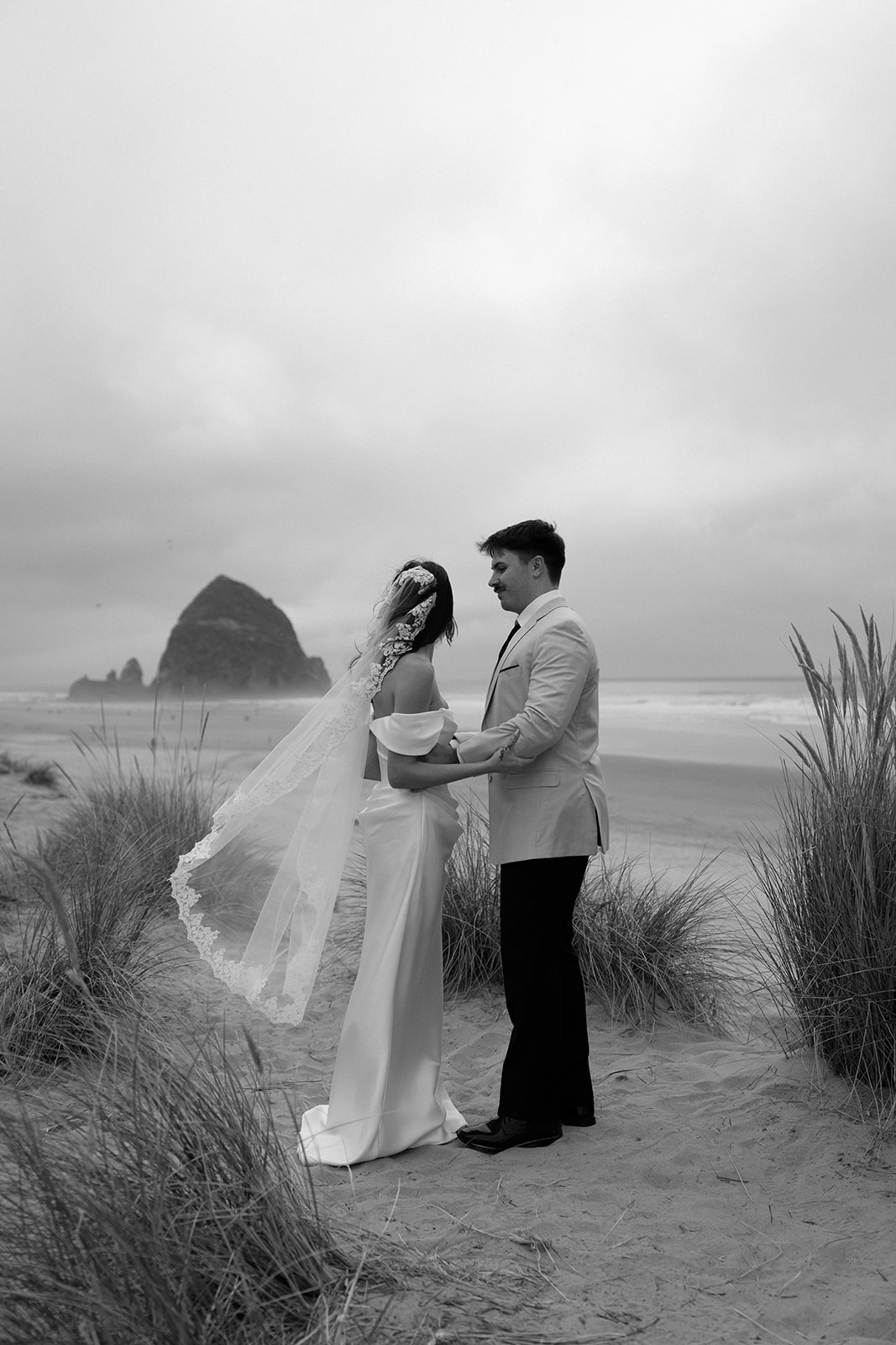 A couple exchanges wedding vows with an officiant in front of Haystack Rock during their Oregon Coast elopement. 