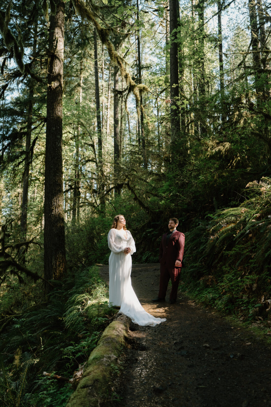 A couple stands in a patch of light in the woods at a Silver Falls elopement