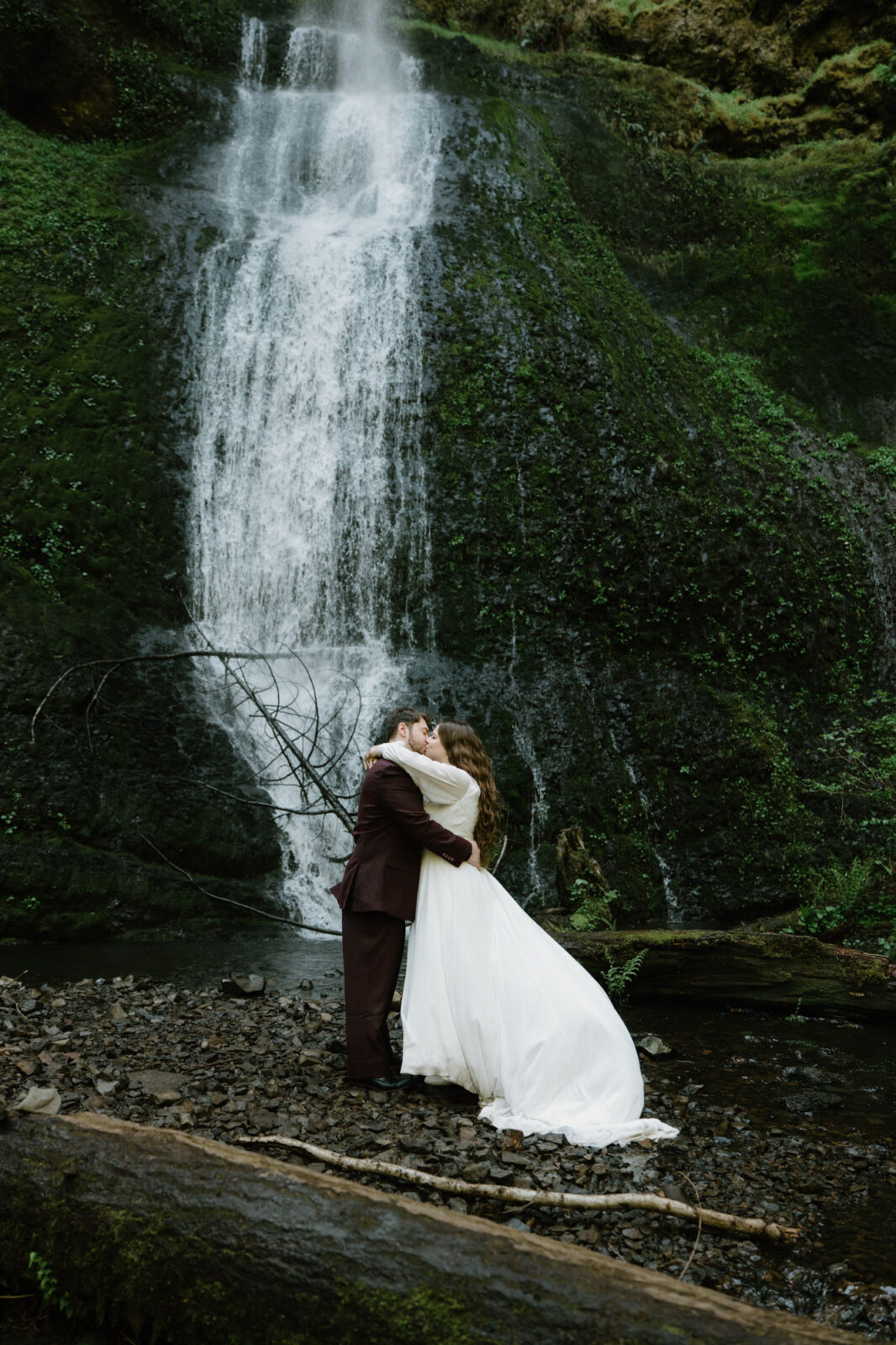 A couple kisses dramatically under a waterfall at a Silver Falls elopement