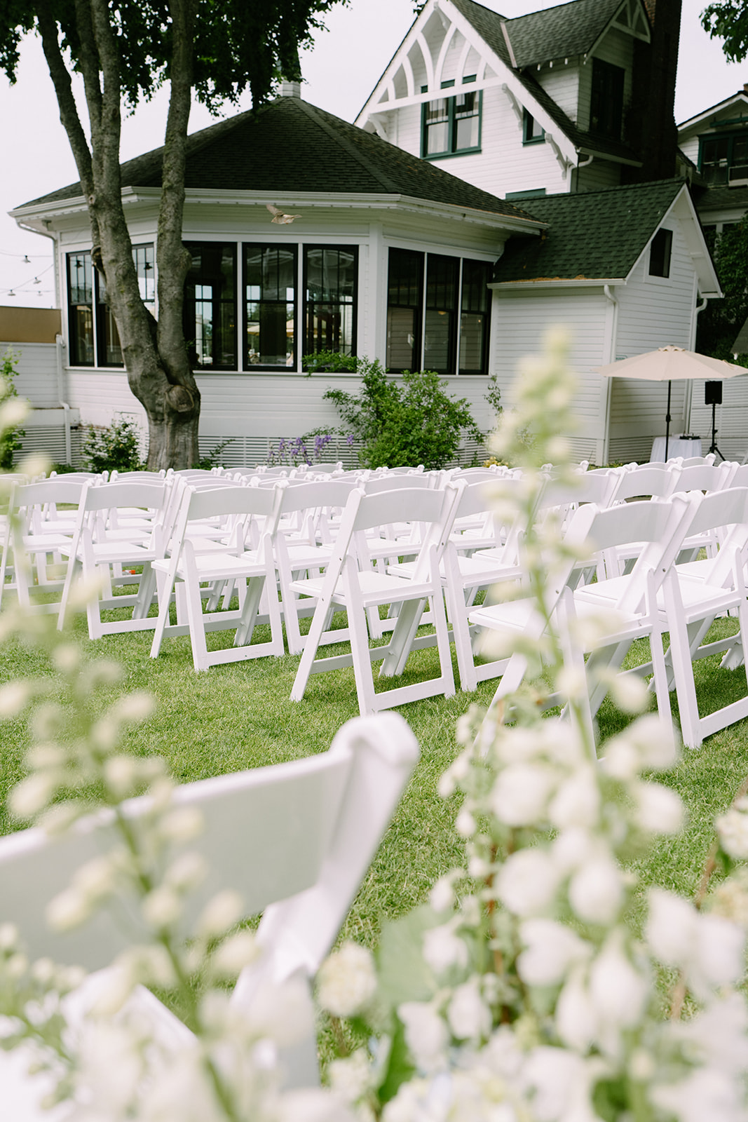 The Roche Harbor Resort garden ceremony space set up for an intimate outdoor wedding on San Juan Island, Washington. Pink peonies in bloom and guests gathering under the summer sky.