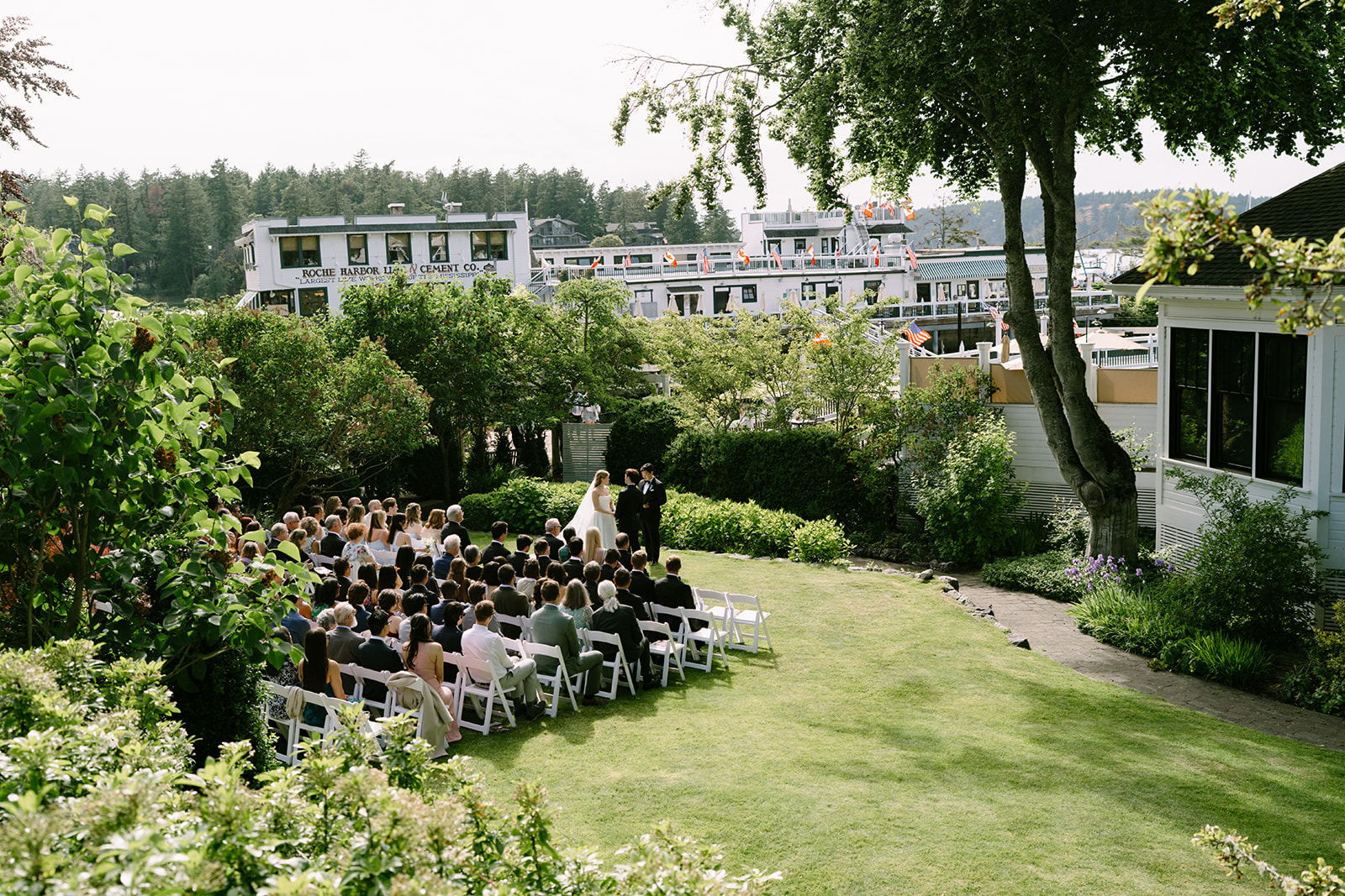 An aerial view of the garden wedding ceremony at Roche Harbor Resort on San Juan Island — surrounded by the lush PNW landscape and the resort marina below.